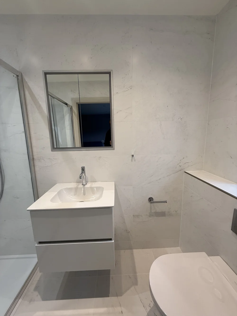 Compact marble ensuite with wall-hung vanity and back-to-wall WC — Godalming bathroom fitters