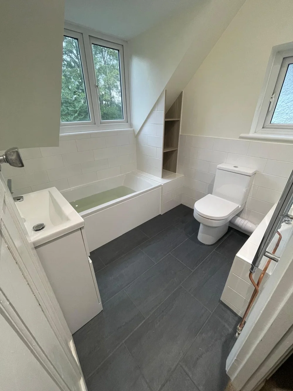 Bright loft family bathroom with metro tiles and slate-tiled floor — bathroom installation Godalming