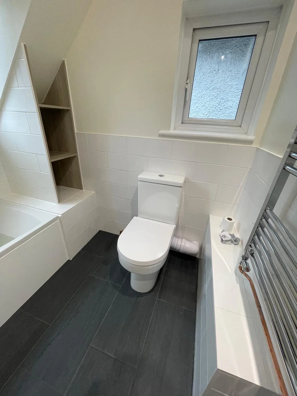 Loft bathroom with metro tiles, bespoke oak shelving and slate floor — bathroom installers Godalming