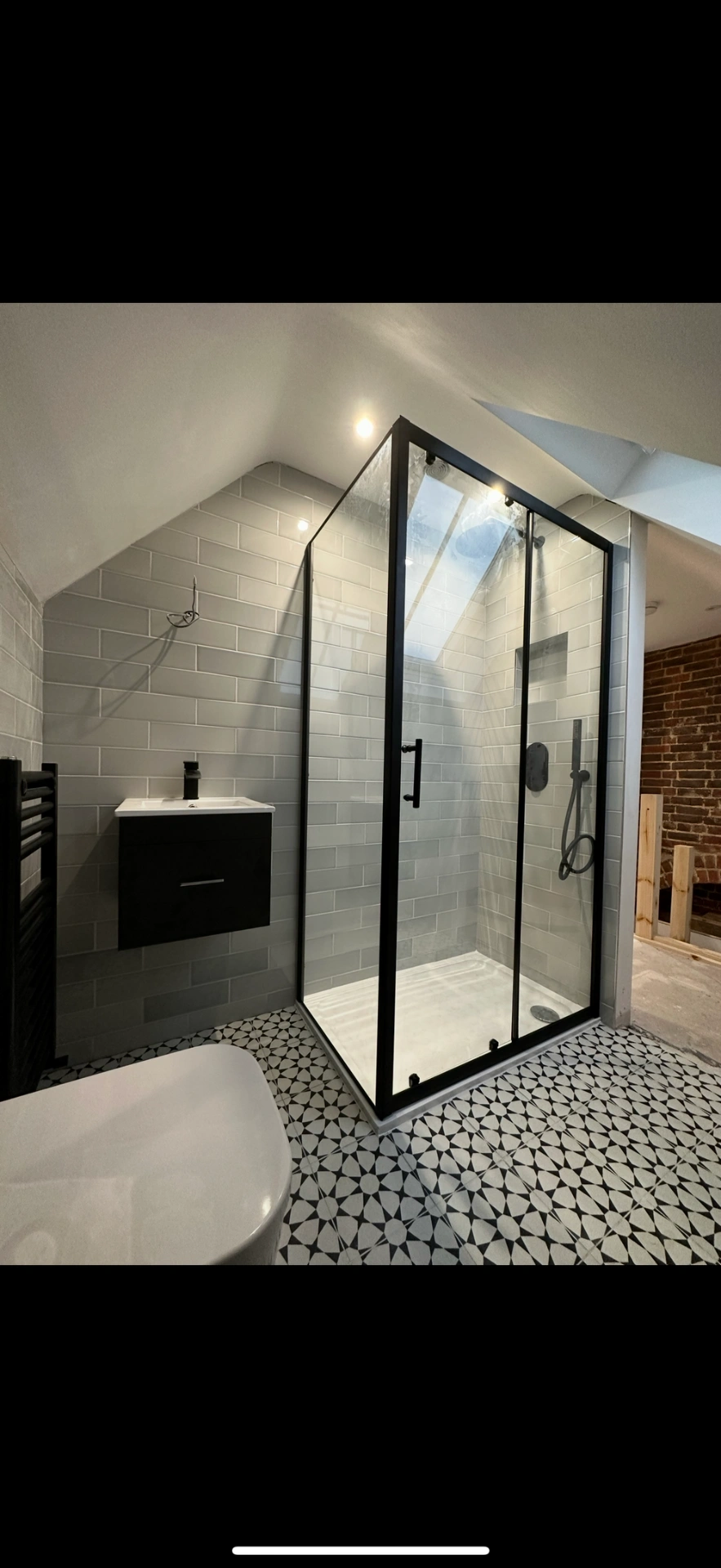 Loft ensuite with matte-black framed shower enclosure and patterned floor — Godalming