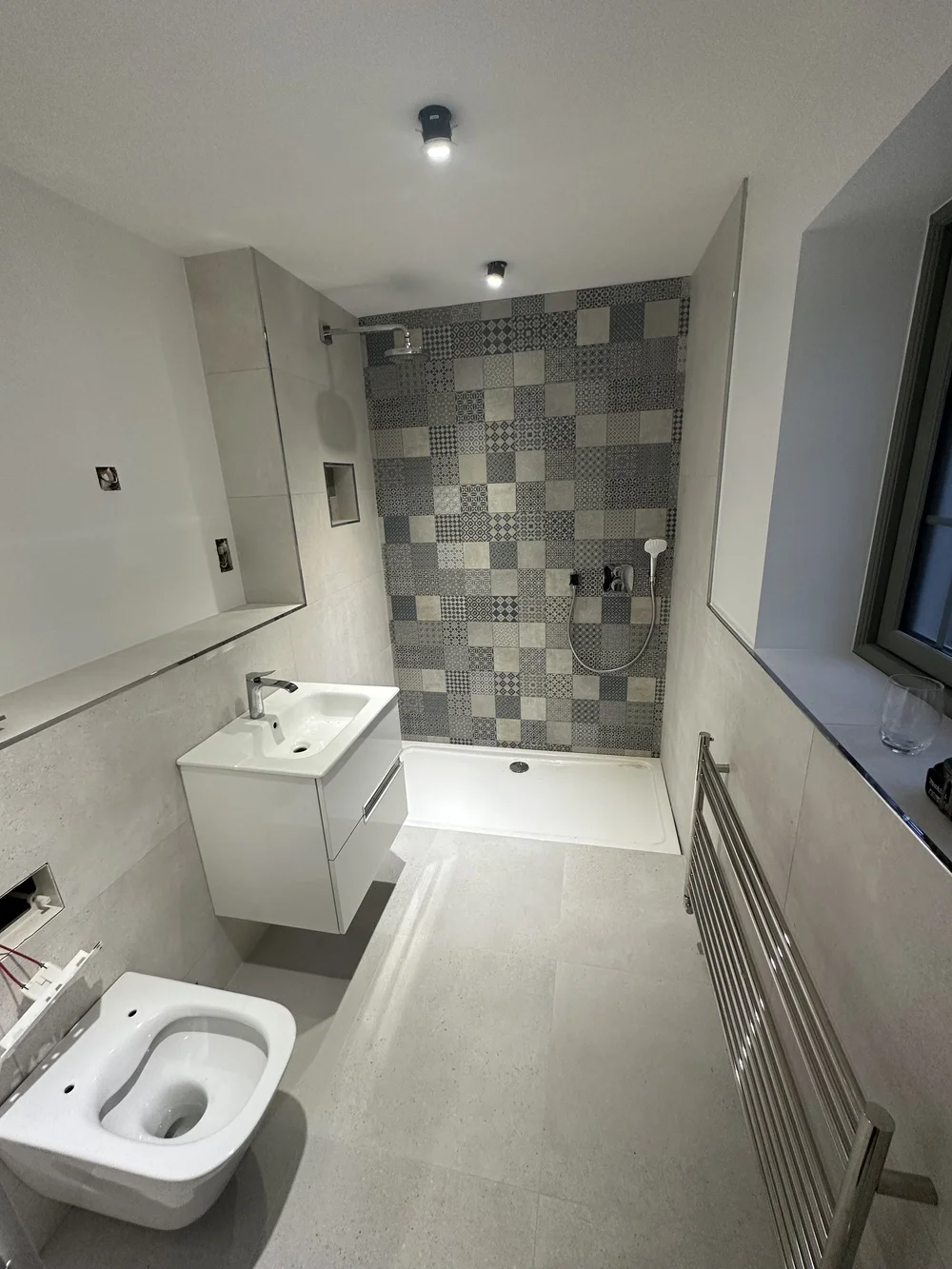 Modern shower room with patchwork feature tiles, white vanity and heated ladder rail — bathroom renovation Godalming