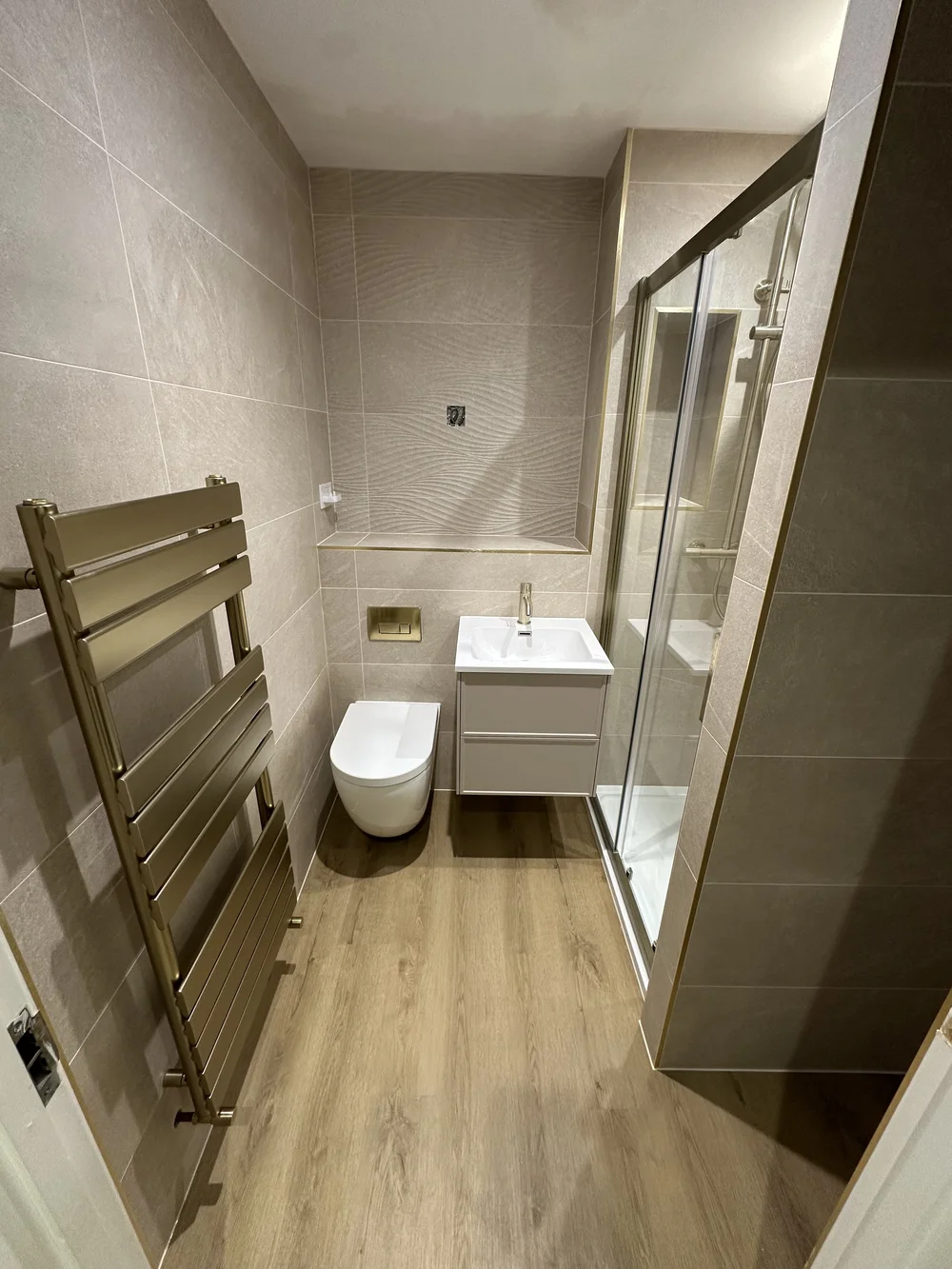 Modern shower room with brushed brass trim, sliding glass door and designer radiator — Godalming bathroom fitters
