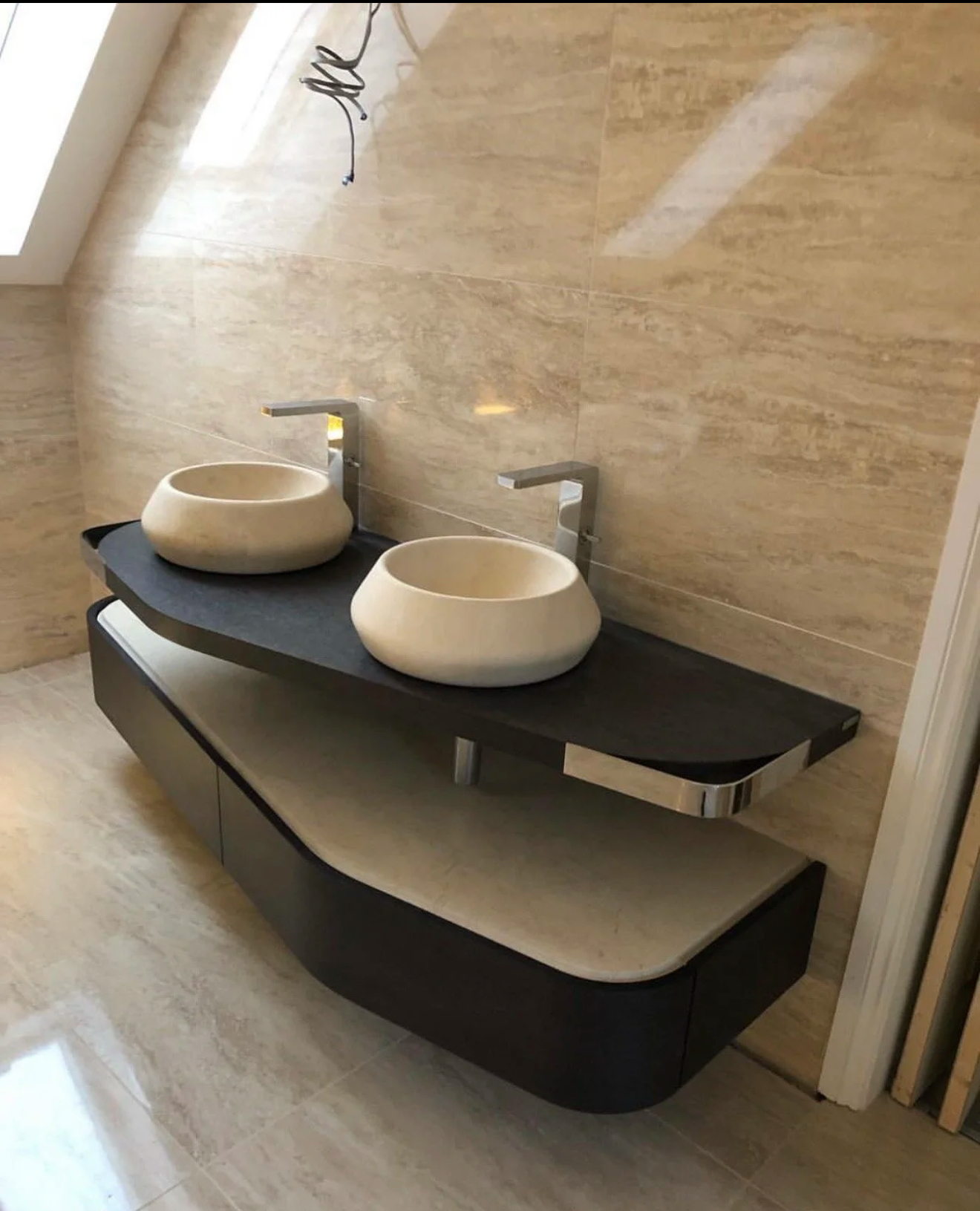 Twin stone vessel basins on a curved dark vanity against travertine walls — recent project Godalming