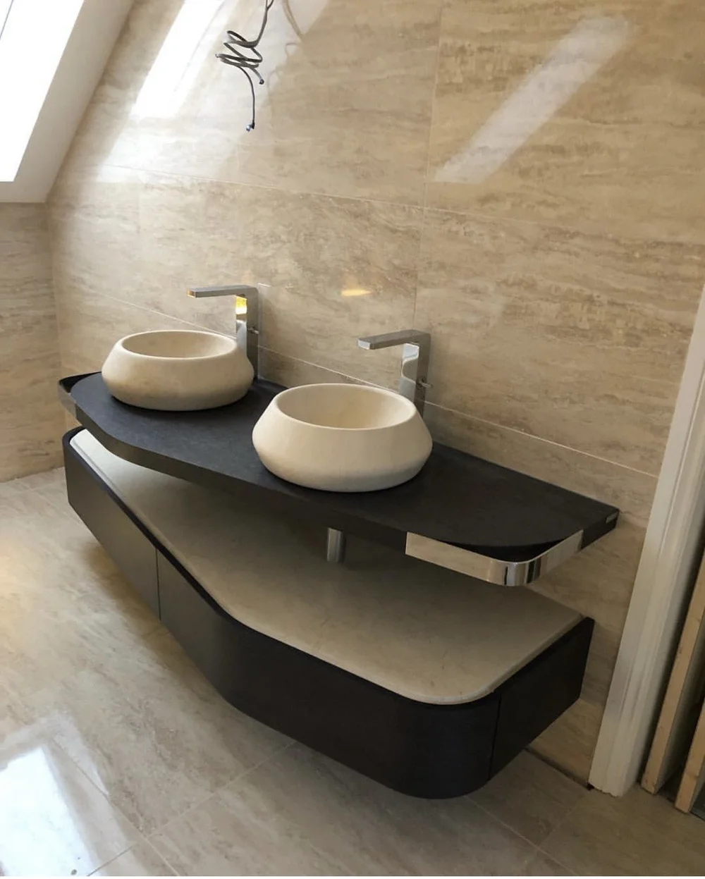 Bespoke twin stone vessel basins on curved slate vanity in travertine ensuite — bathroom design Godalming
