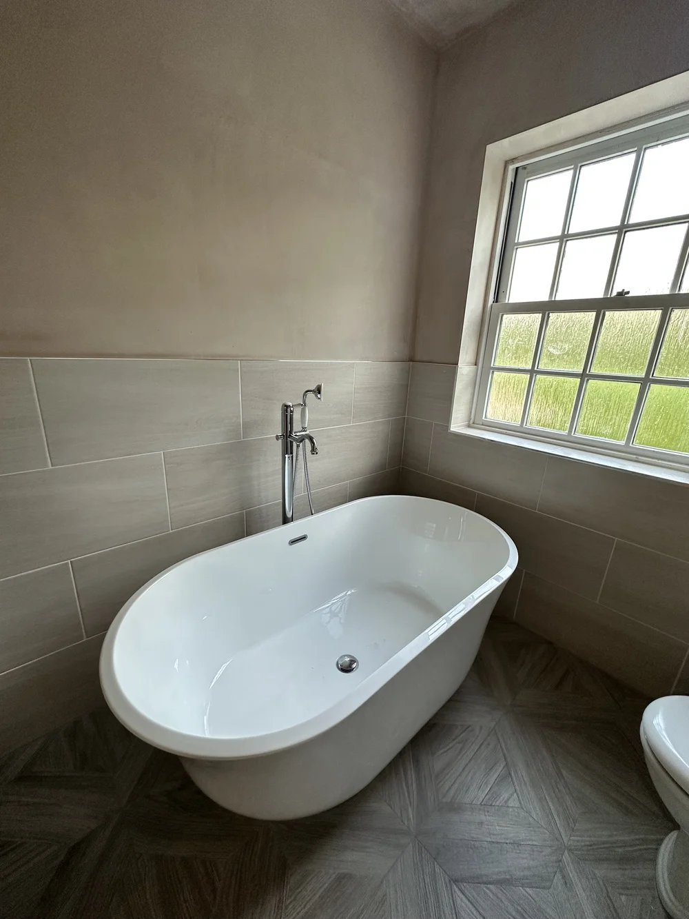 Traditional freestanding double-ended bath with chrome floor-mounted mixer and parquet floor — bathroom installation Godalming