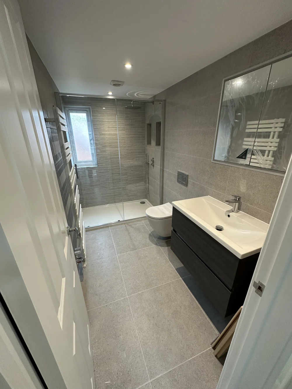 Grey stone-tiled shower room with graphite vanity and glass shower enclosure — bathroom installation Godalming