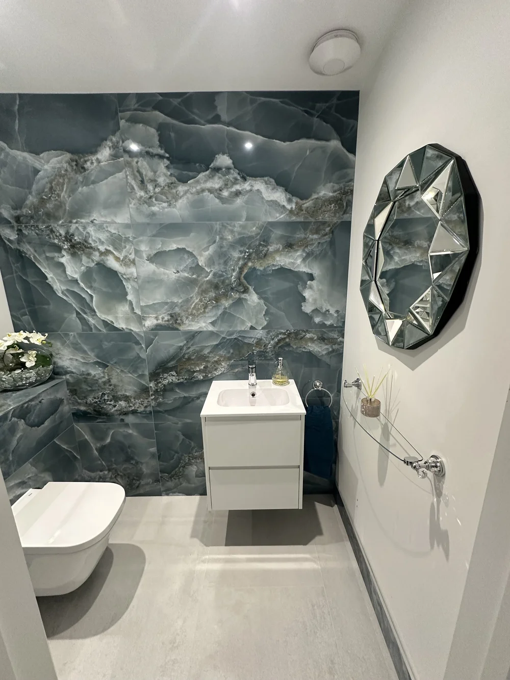 Luxury cloakroom with blue onyx feature wall, wall-hung WC and jewel-cut mirror — bathroom installation Godalming