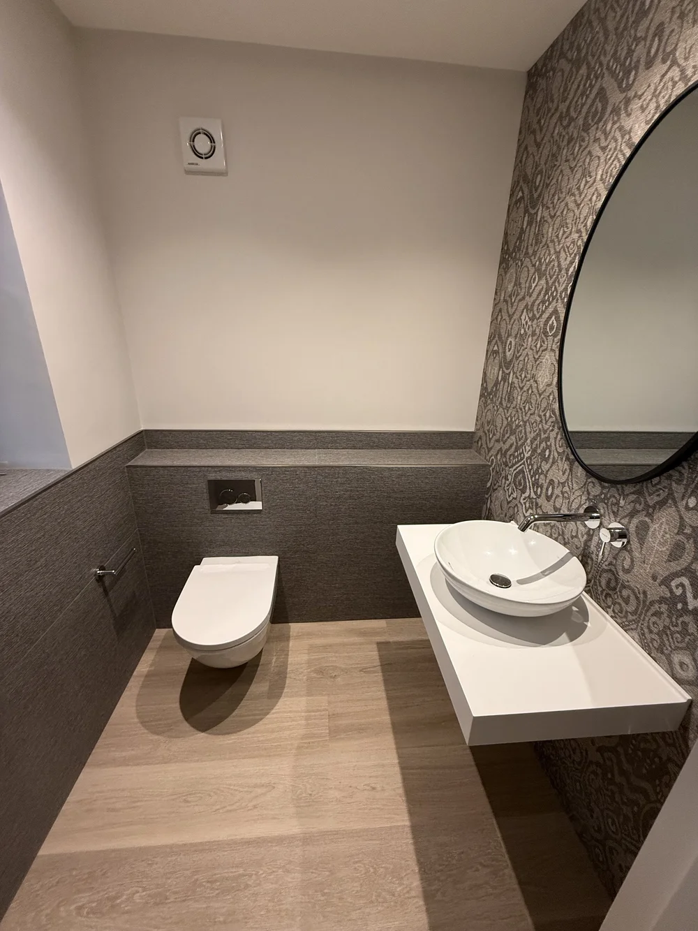 Bespoke cloakroom with patterned wallpaper, oak floor and floating vessel basin — Godalming