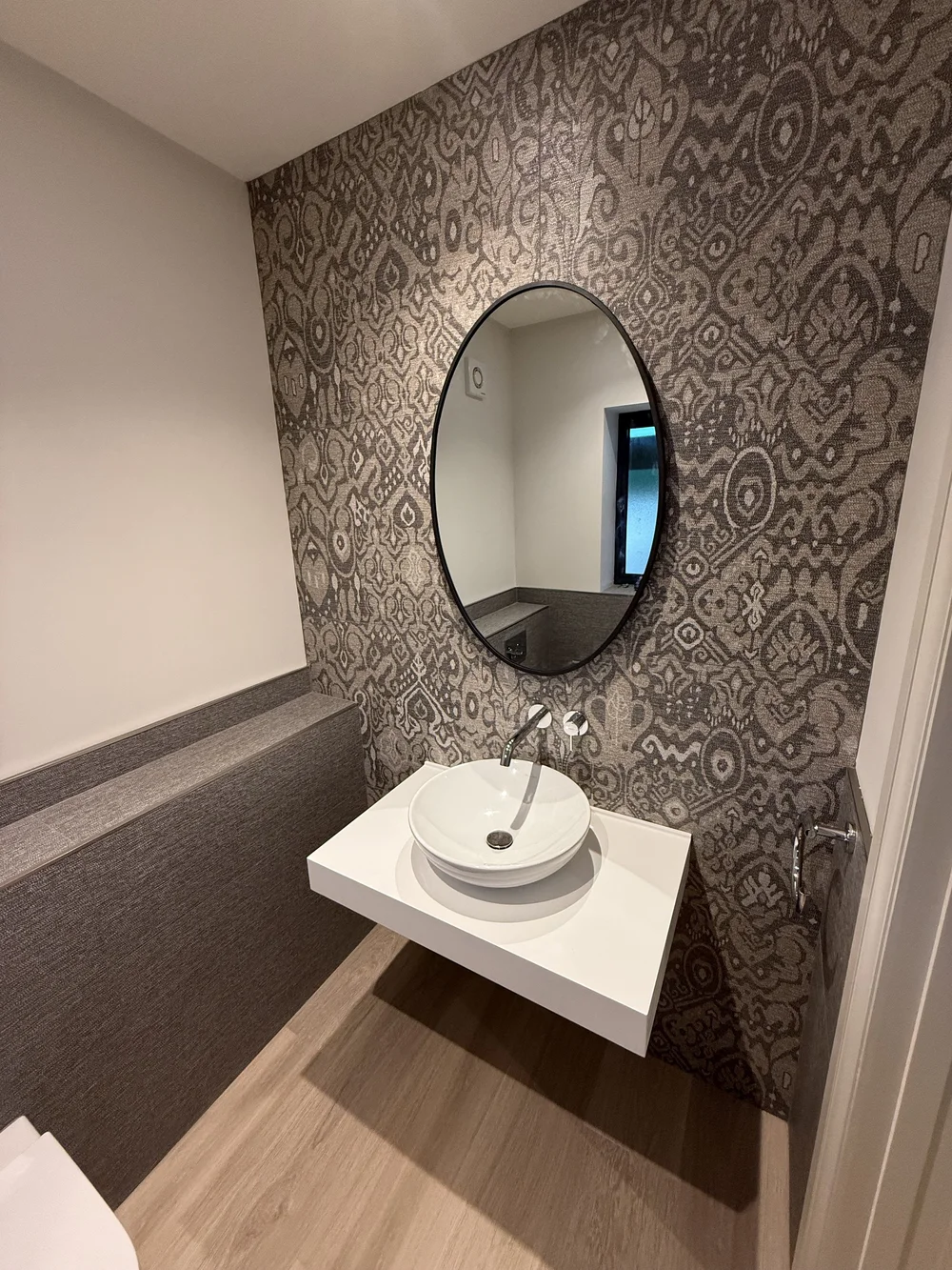 Feature-wall cloakroom with round black mirror and vessel basin — bathroom design Godalming