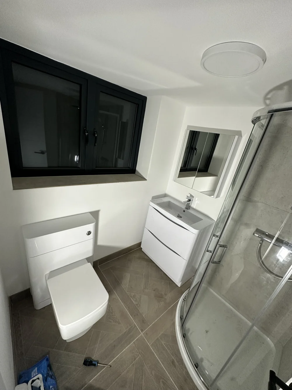 Compact ensuite with quadrant shower enclosure, wall-hung vanity and back-to-wall WC — bathroom installation Godalming