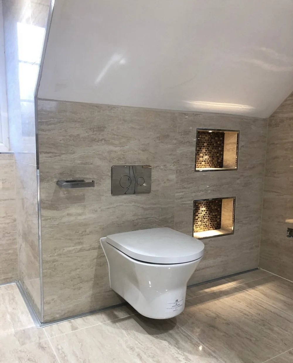 Travertine wet room with wall-hung WC and illuminated mosaic niches — bathroom renovation Godalming