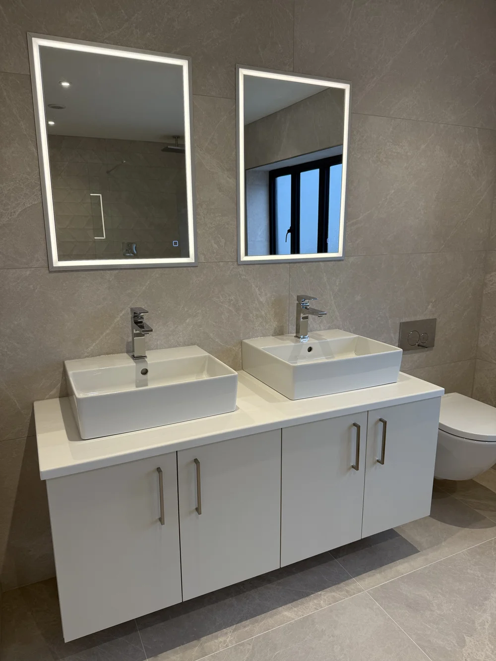 Twin countertop basins with LED mirrors on wall-hung vanity — ensuite installation Godalming