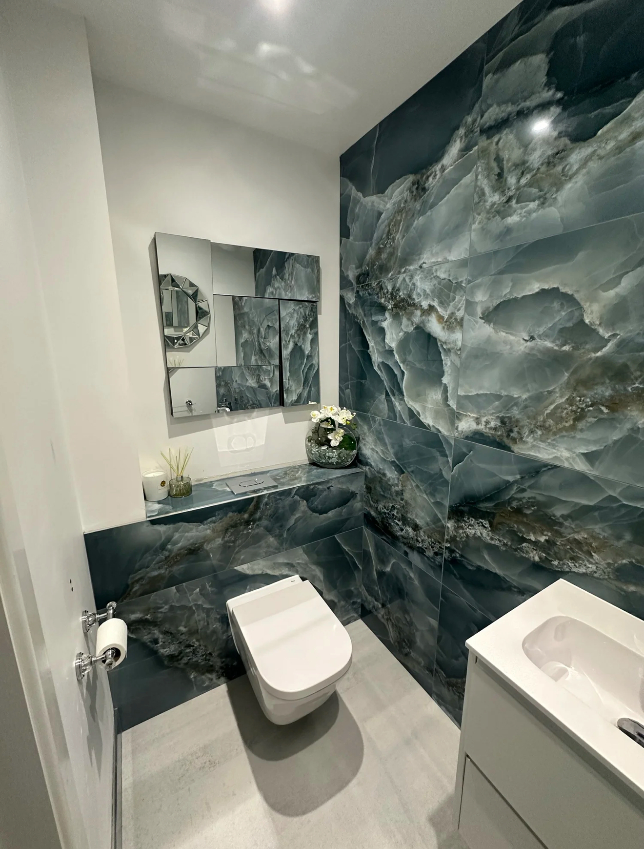 Cloakroom with blue-green onyx marble feature wall and mirrored cabinet — recent project Godalming