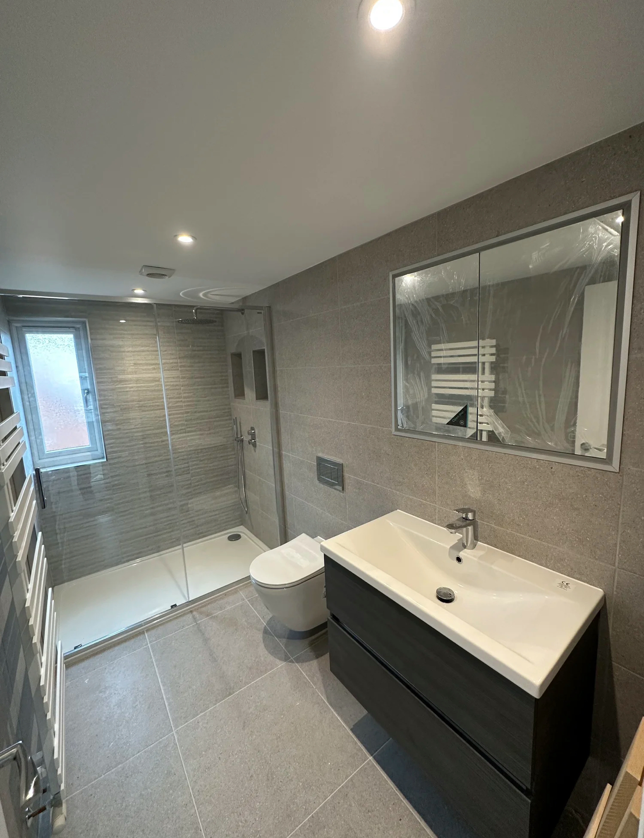 Grey tiled shower room with graphite vanity and mirrored cabinet — recent project Godalming