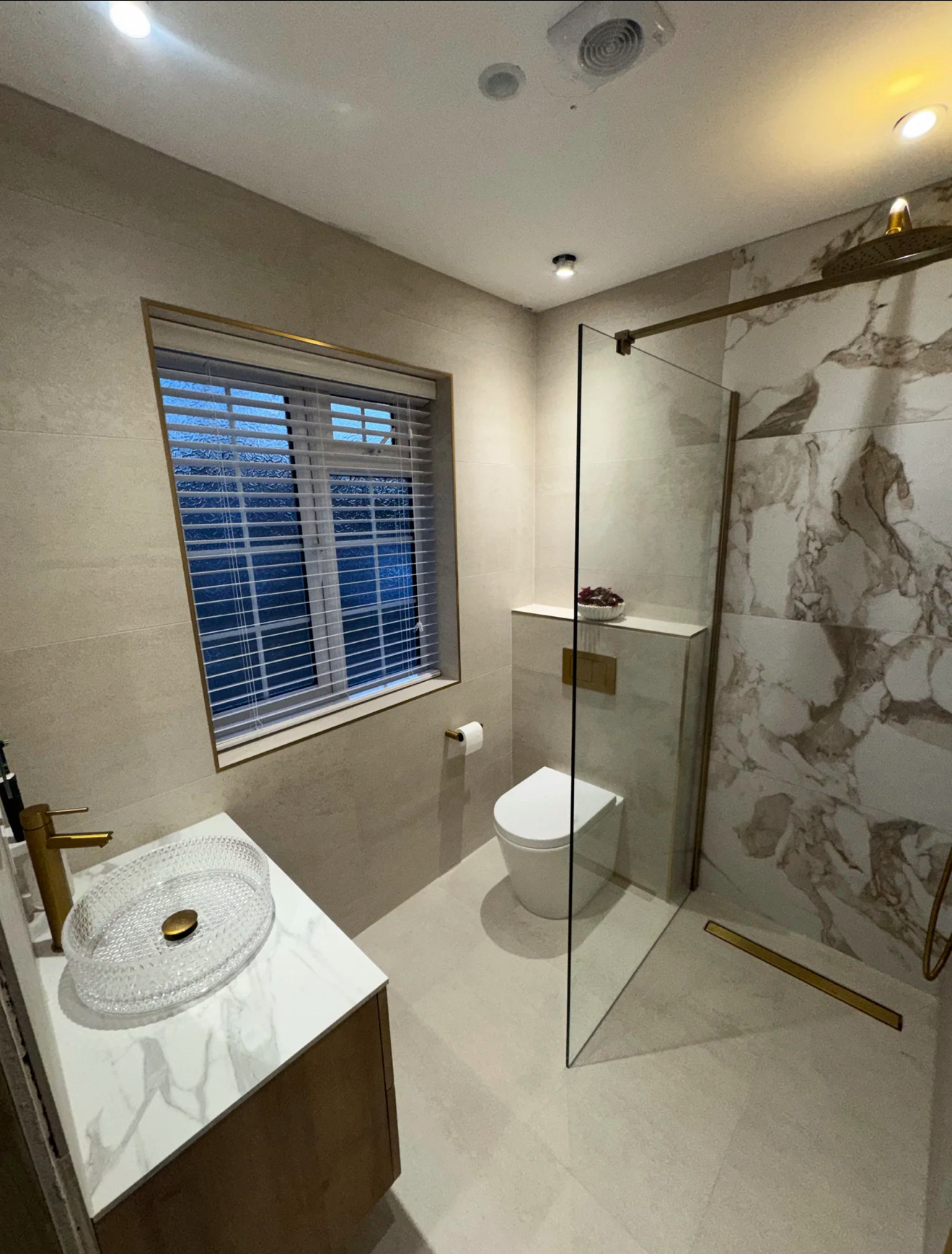 Brass-finished wet room with marble shower wall and vessel basin — recent project Godalming