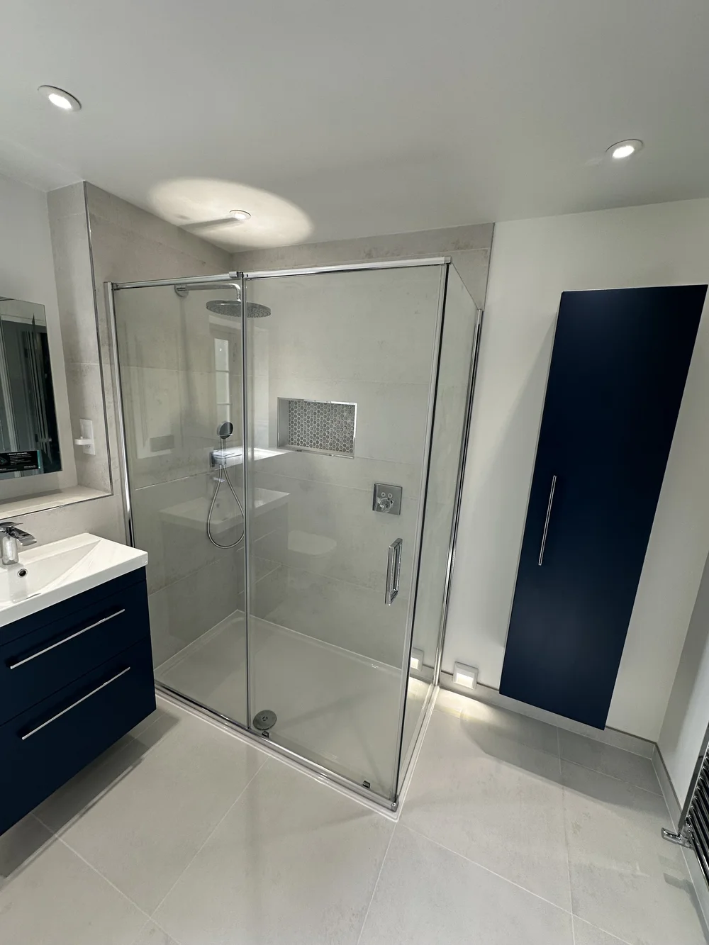 Contemporary shower room with navy wall cabinet, floating vanity and walk-in shower — bathroom installation Godalming
