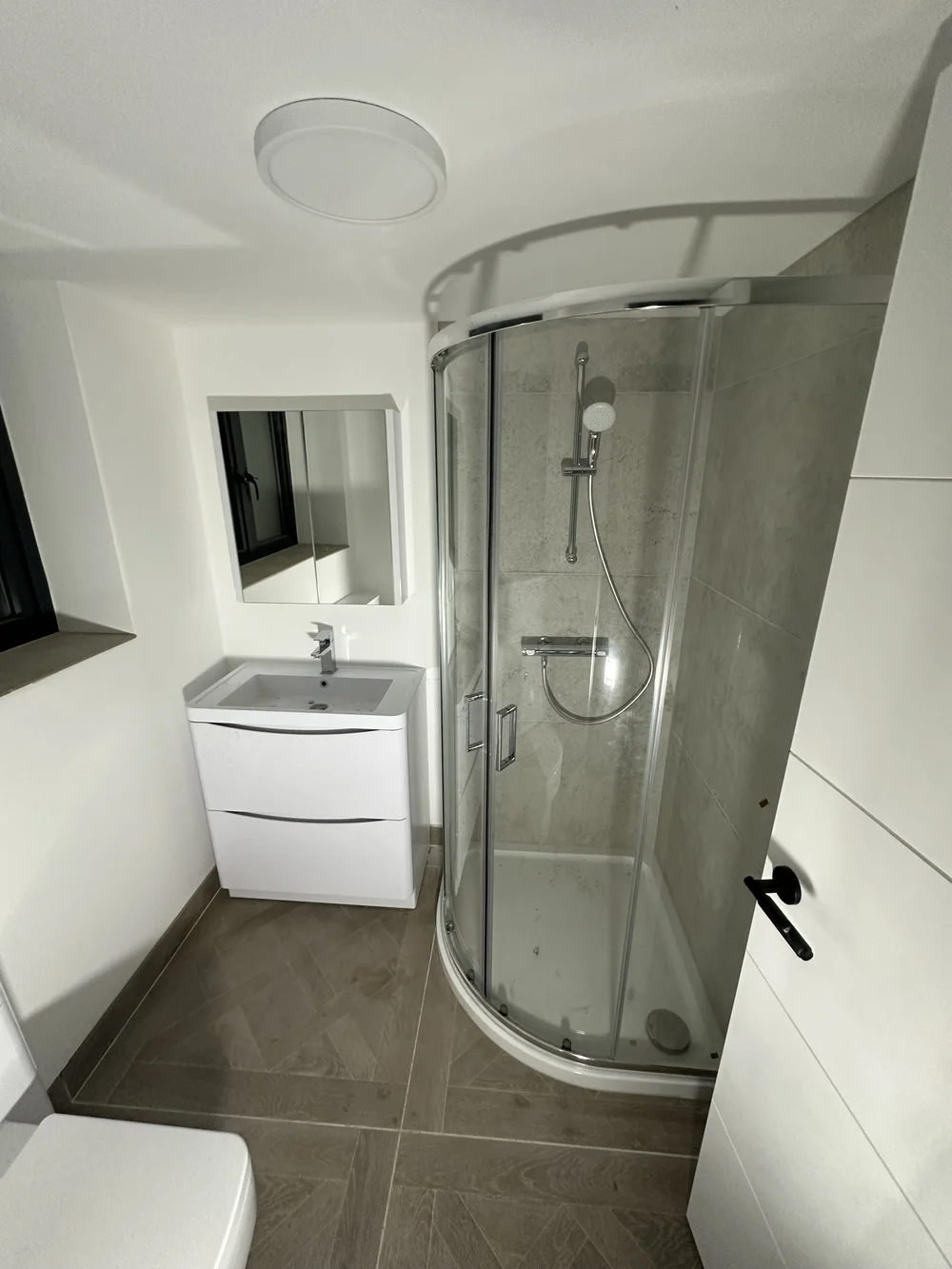 Loft shower room with quadrant enclosure, herringbone tile floor and floor-standing vanity — bathroom installation Godalming