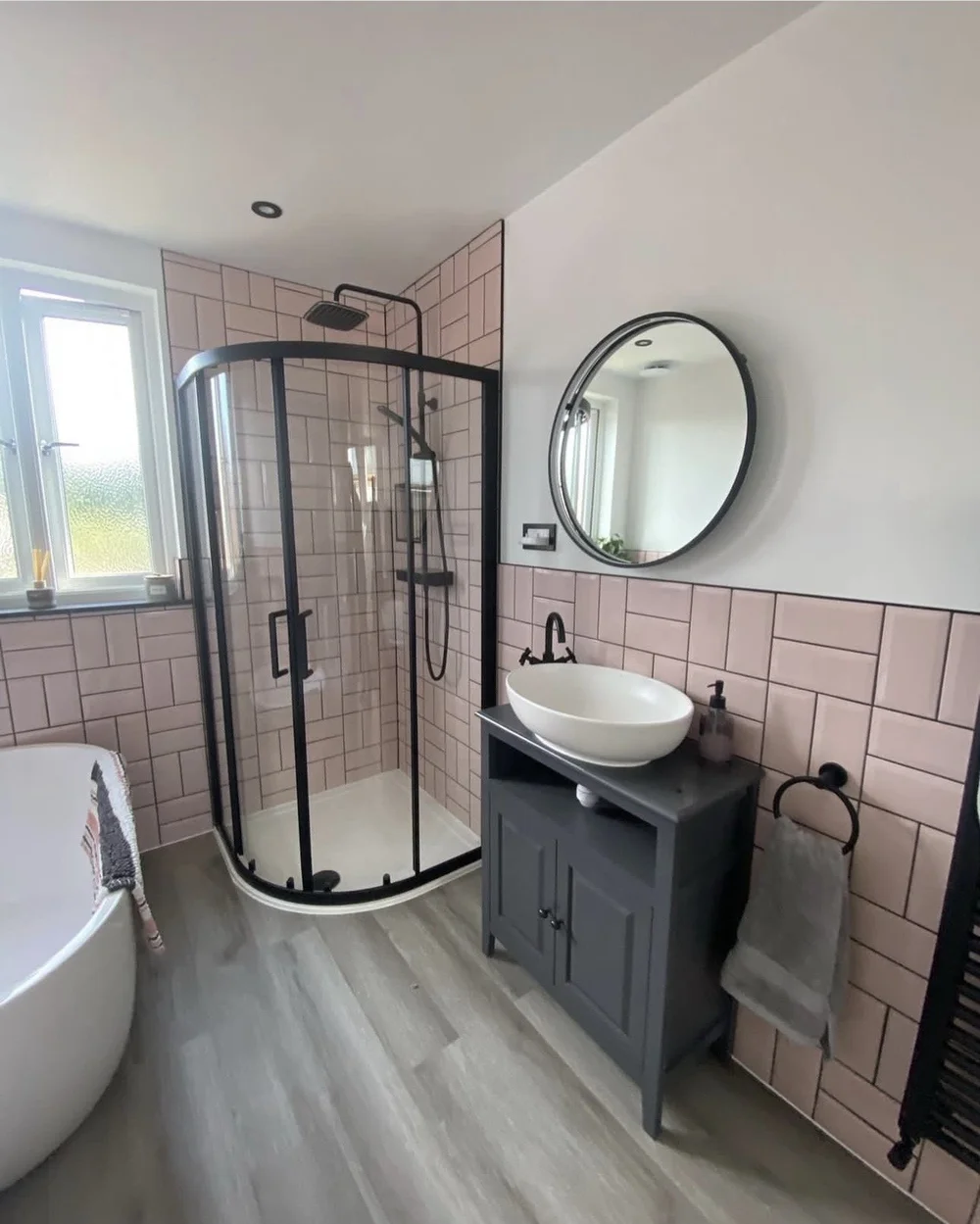Pink metro-tiled bathroom with black-framed quadrant shower, freestanding bath and vessel basin — bathroom renovation Godalming