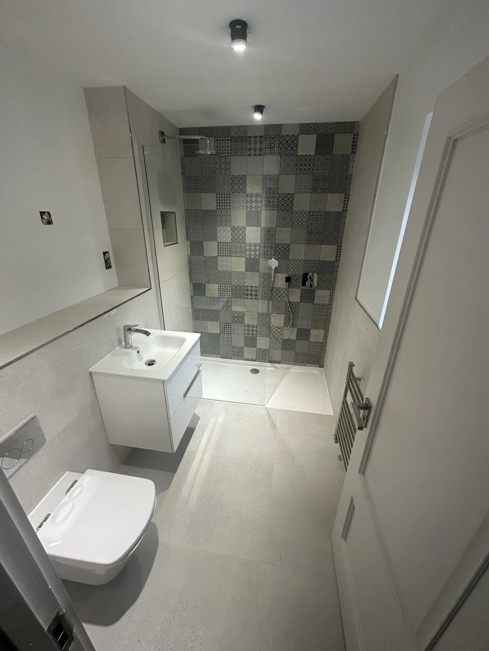 Compact shower room with patchwork feature wall and floating white vanity — bathroom installation Godalming