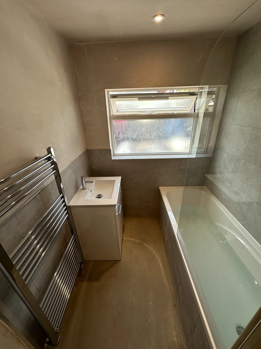 Compact family bathroom mid-renovation with fresh plaster, stone tiling and new bath — bathroom renovation Godalming