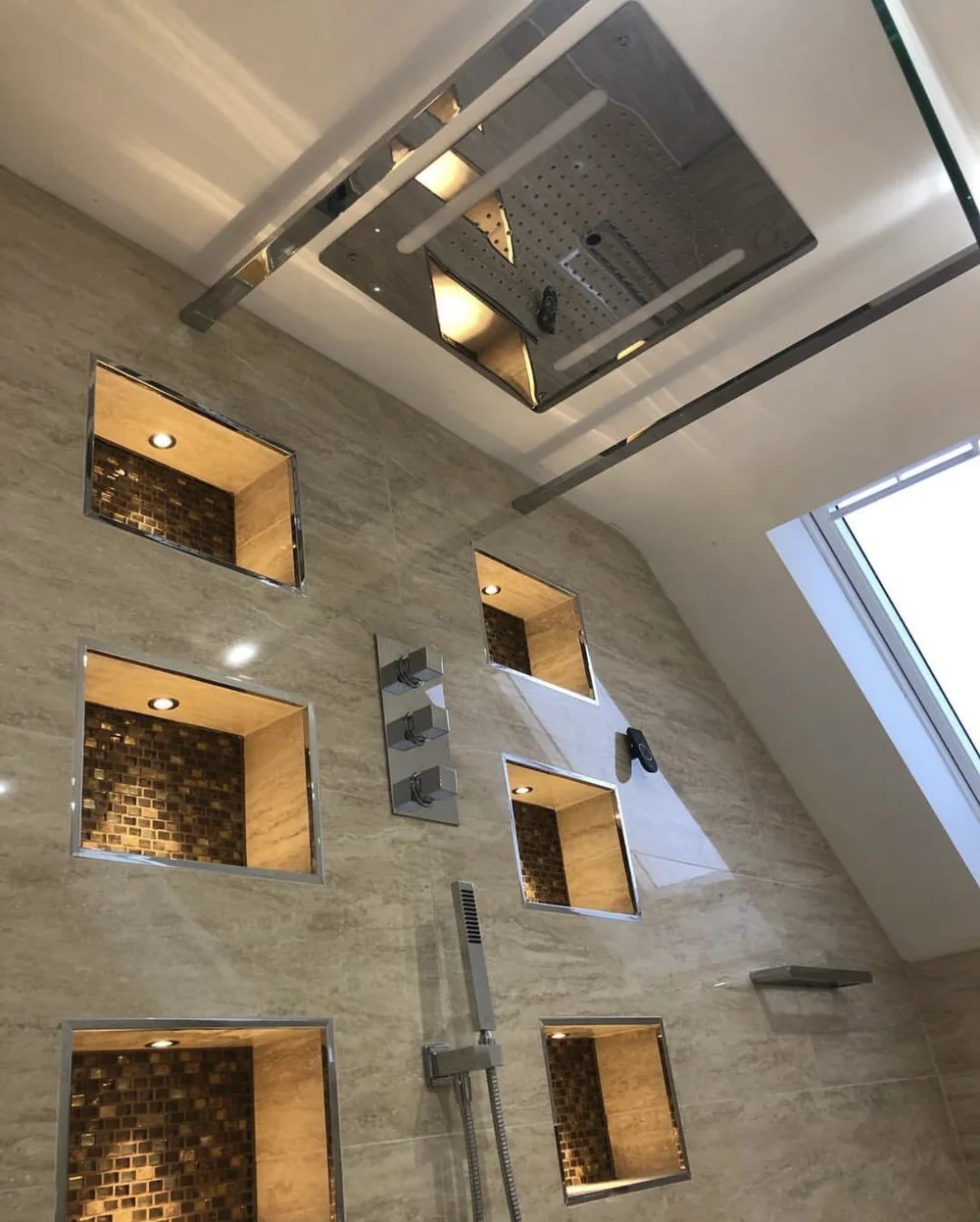Ceiling rainfall panel with LED strip lighting over travertine walk-in shower — luxury bathroom installation Godalming