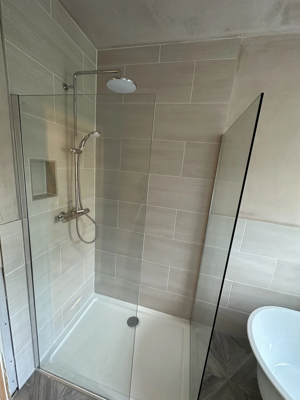 Walk-in shower with cream metro tiles, brushed nickel rainfall column and glass screen — bathroom installation Godalming